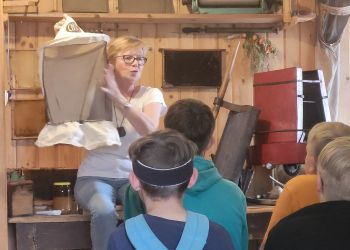 Powiększ zdjęcie: kobieta pokazująca ubiór pszczelarza