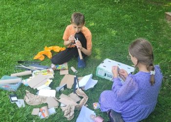 Powiększ zdjęcie: dzieci siedzące na trawie