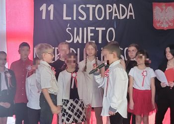 Powiększ zdjęcie: dzieci na scenie - z tyłu dekoracja z napisem 11 Listopada Święto Niepodległości